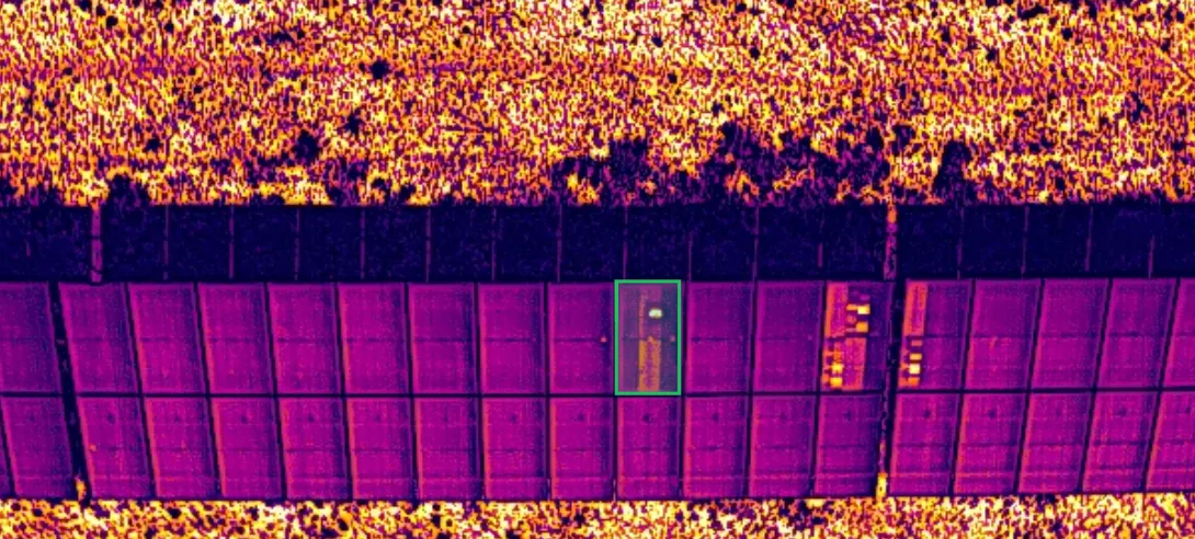The drone's raw thermal frame. A row of panels; the hot spot on the panel marked with a green box stands out clearly.